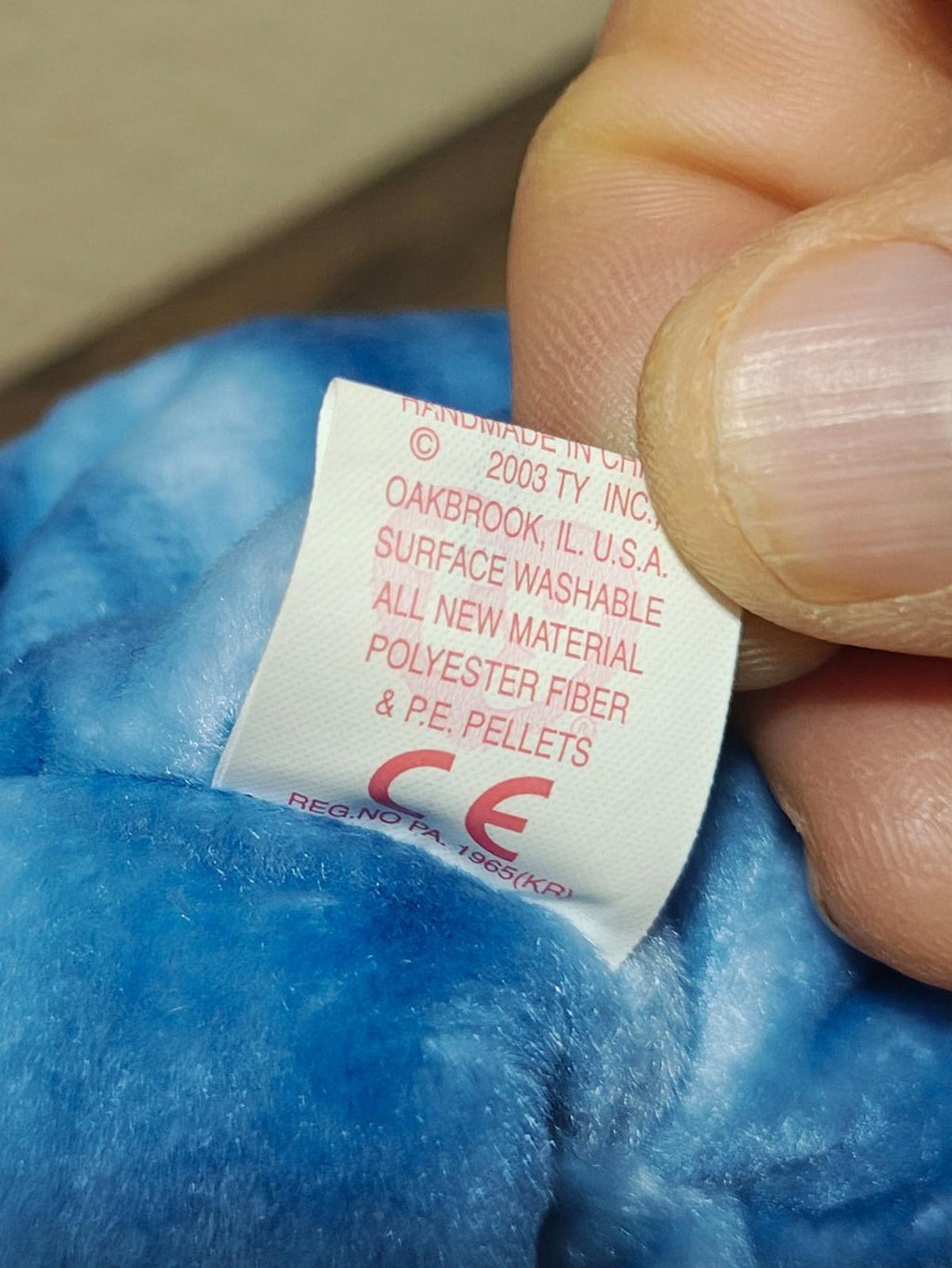 Blue bear plush fabric label close-up with care instructions and brand marks