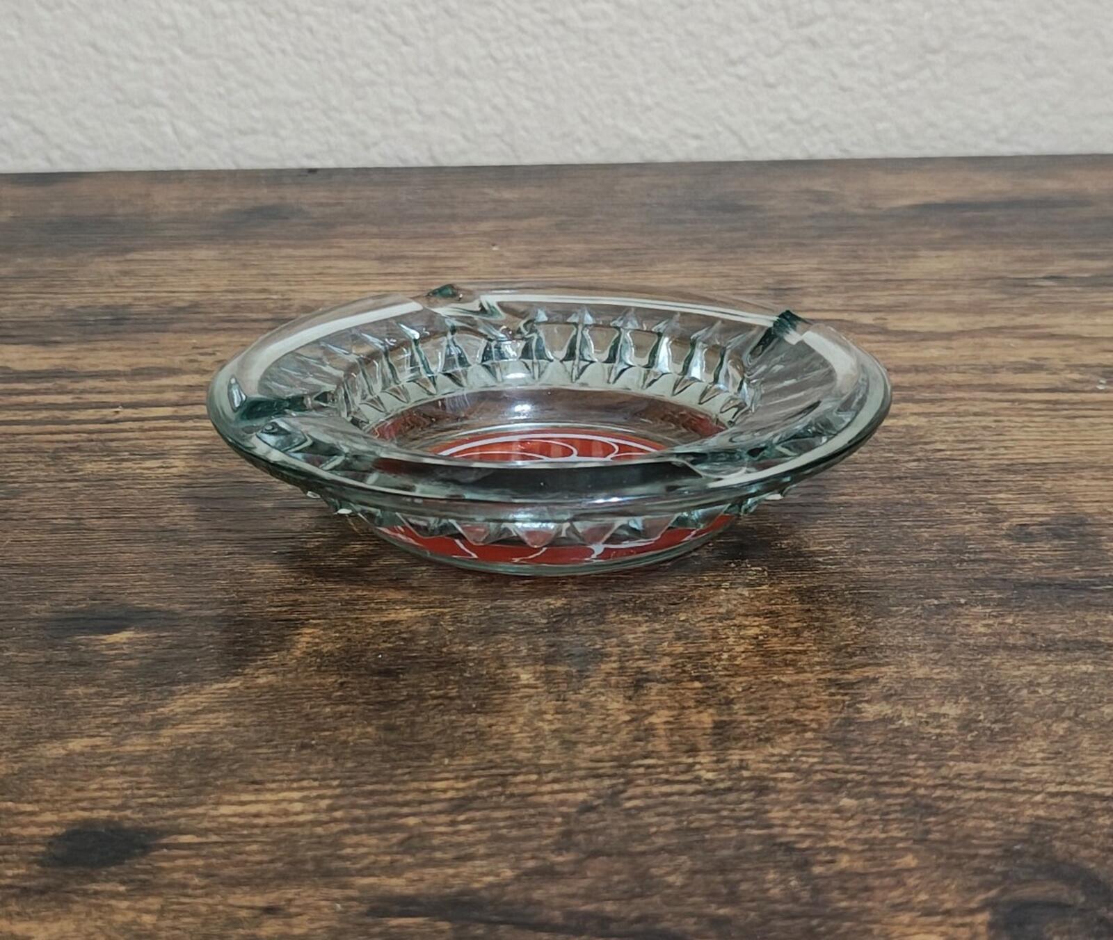 Clear glass ashtray, open top facing up with red logo visible