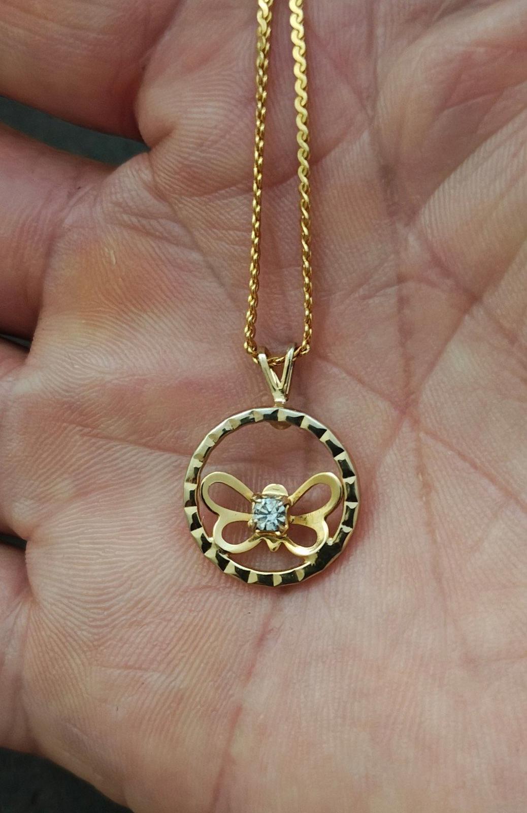 Gold-tone round pendant necklace with open circle border, butterfly bow motif, clear rhinestone