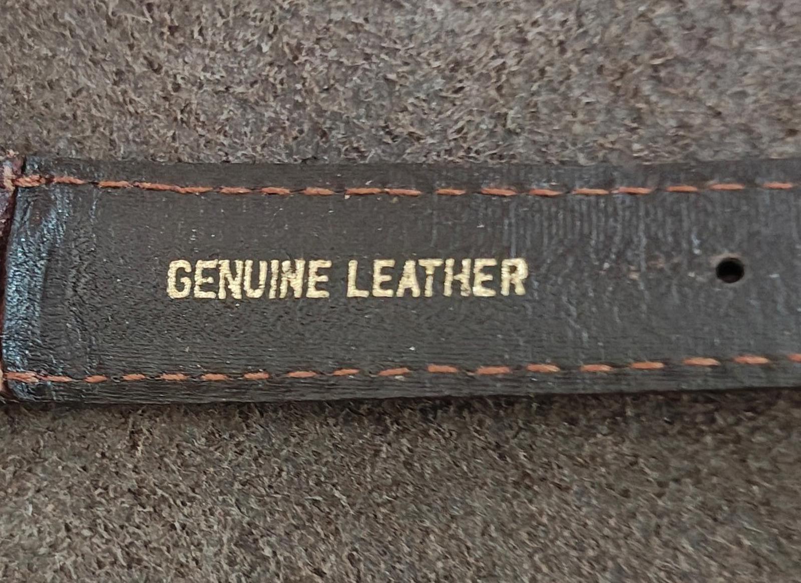 Brown leather watch strap close-up with “GENUINE LEATHER” and orange stitching