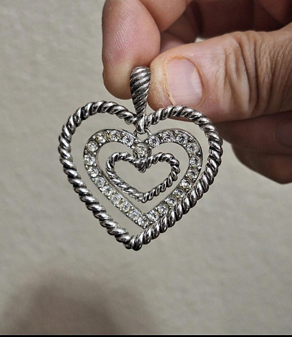 Silver heart pendant close-up: rope rim, rhinestone frame, and loop bail