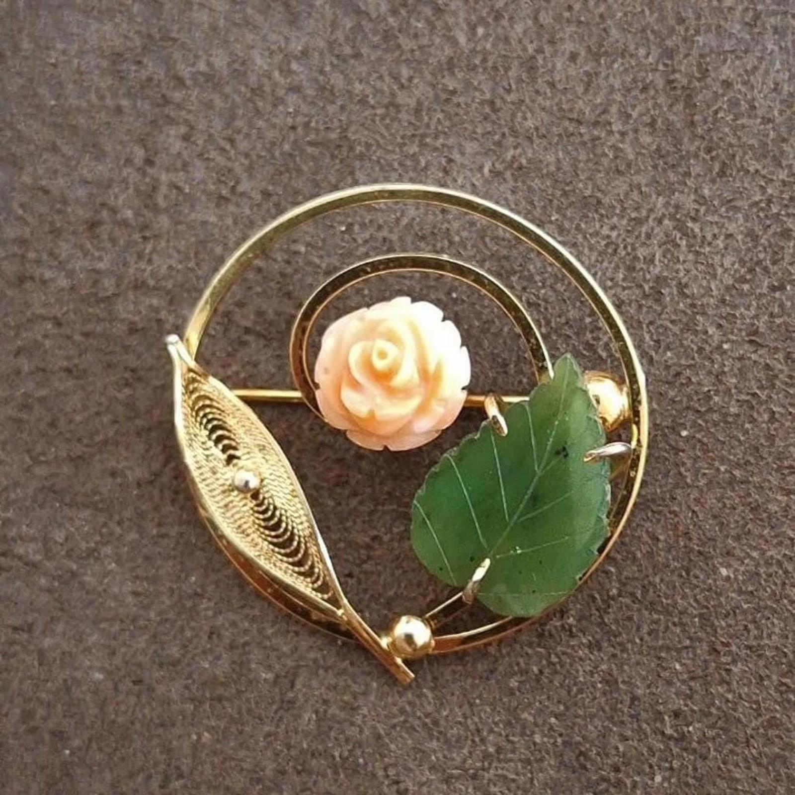 Gold-tone brooch with pale rose centerpiece and green leaf details in filigree.