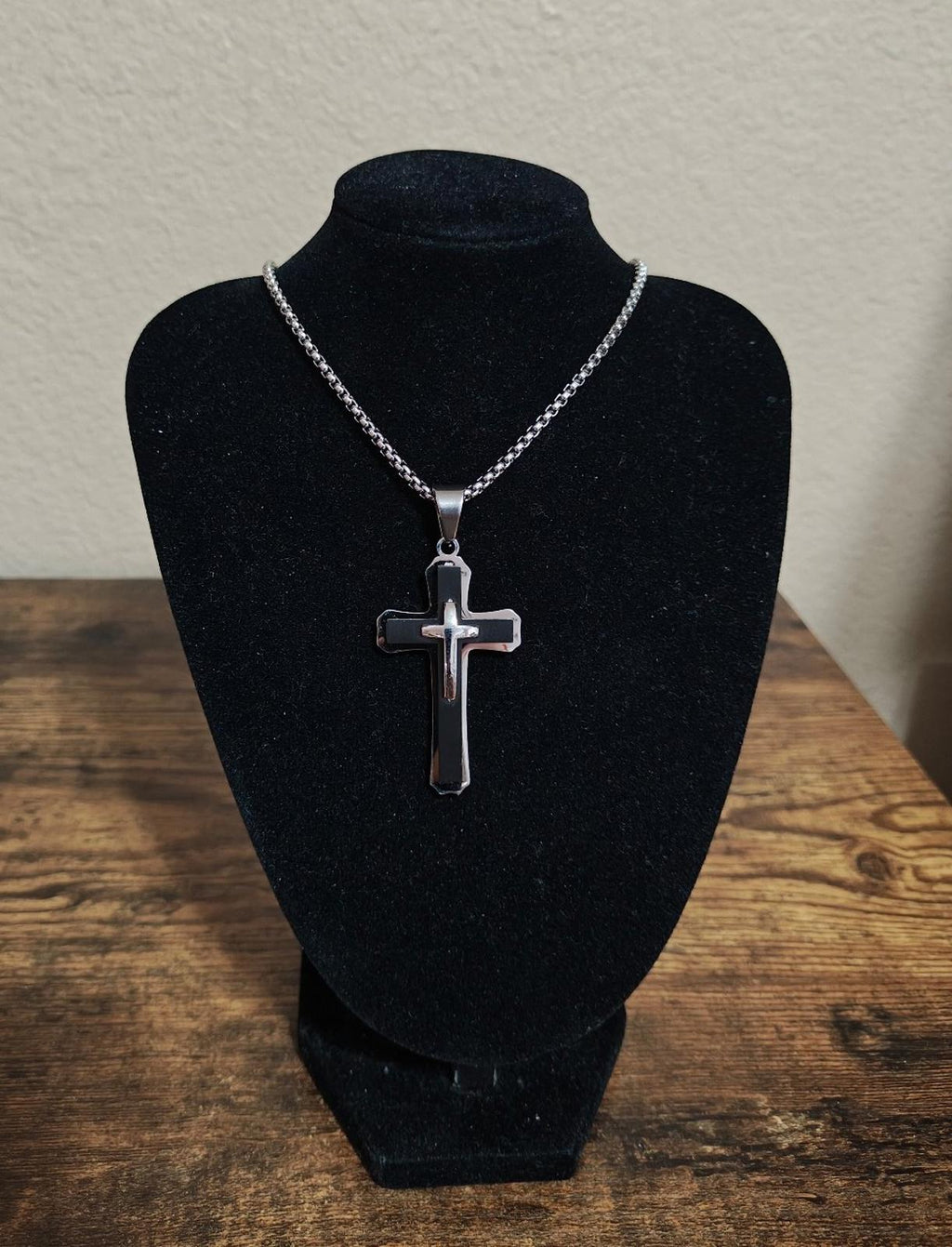 Cross pendant necklace on a black display bust with silver-tone chain