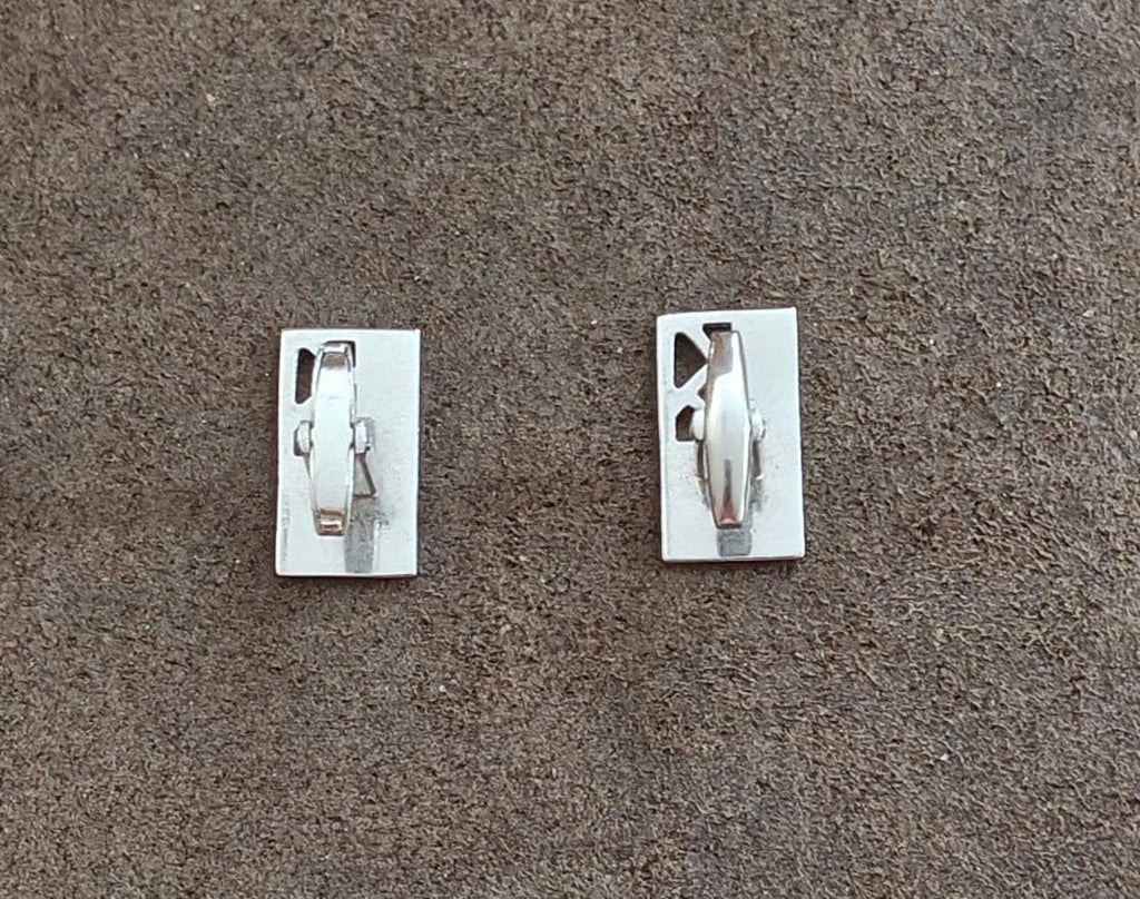 Silver-tone cufflink back plates with visible hinge and pin components
