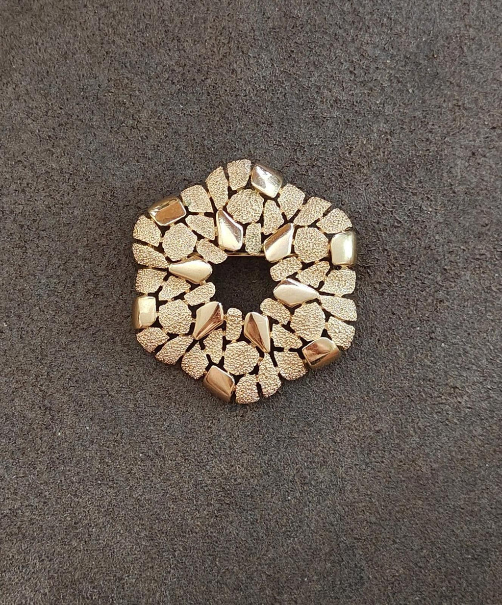 Gold-tone cobblestone wreath brooch on dark background, open circle