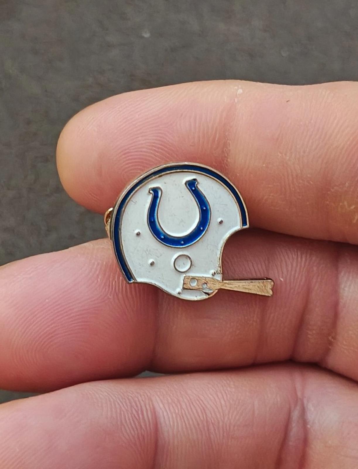Gold-tone enamel tie clip showing a white helmet with blue horseshoe center