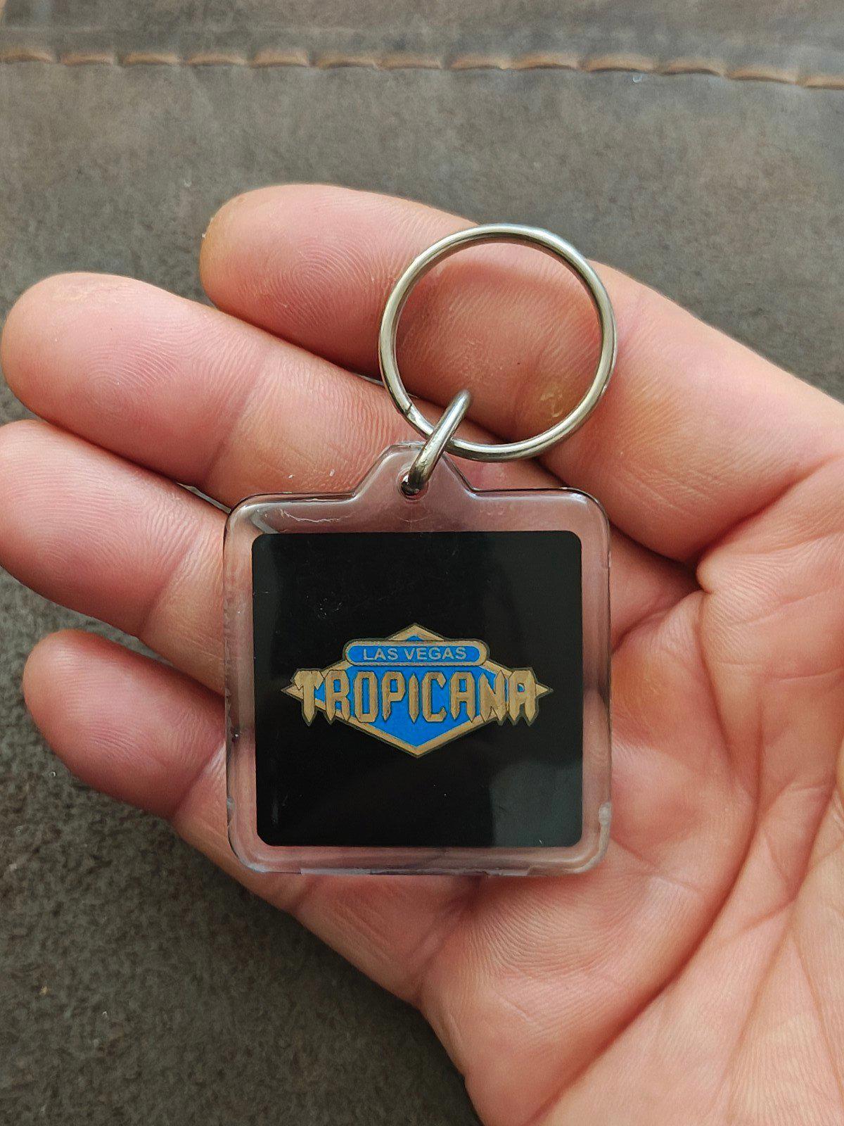 Square Tropicana logo keychain badge with metal ring in hand close-up
