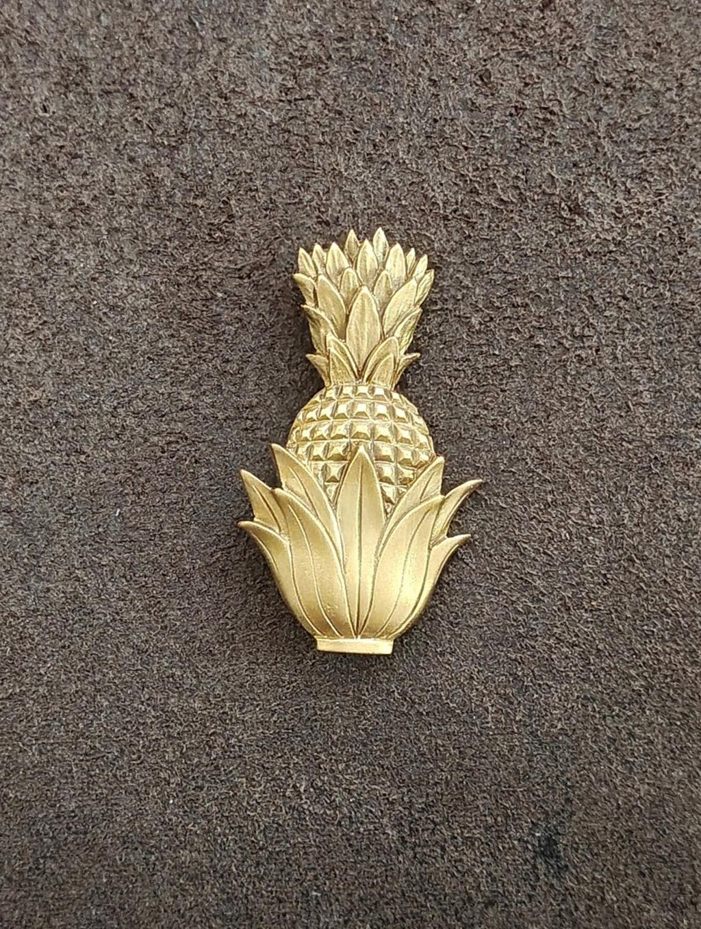 Gold-tone pineapple brooch featuring raised pineapple scales and leaf fronds