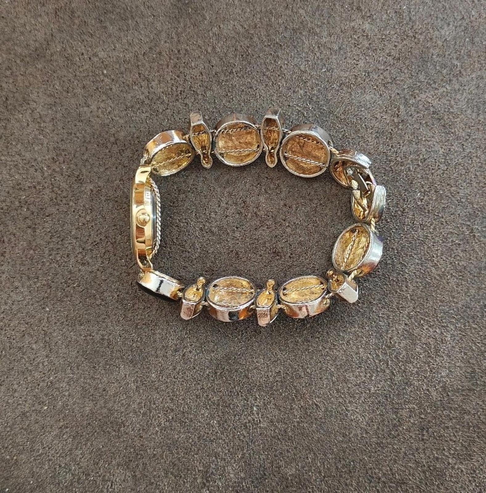 Gold-tone bracelet with oval black links, white beads, and small red accents