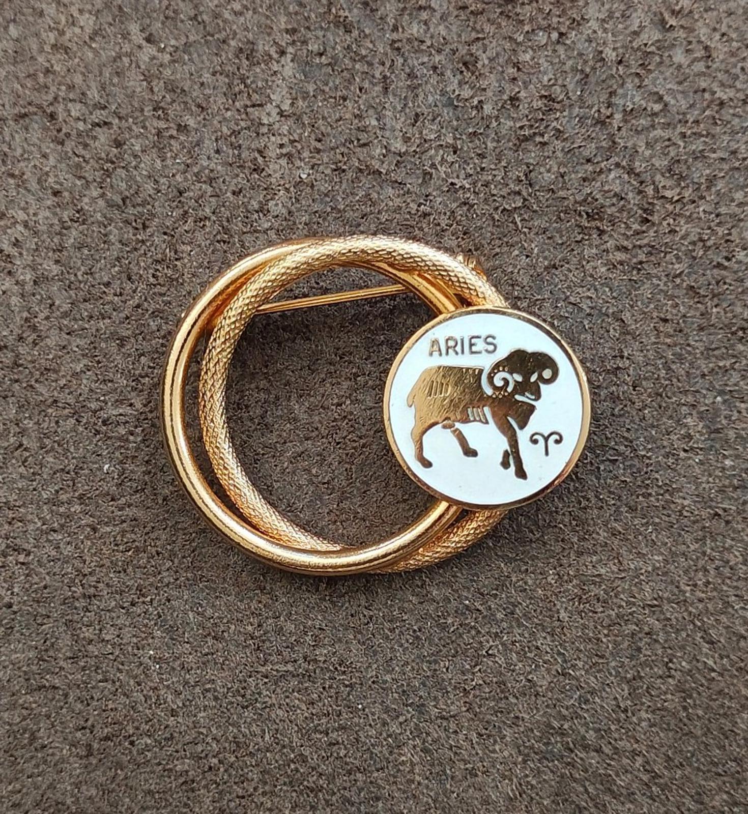 Gold tone double-circle brooch pin with white enamel Aries medallion on gold rope ring
