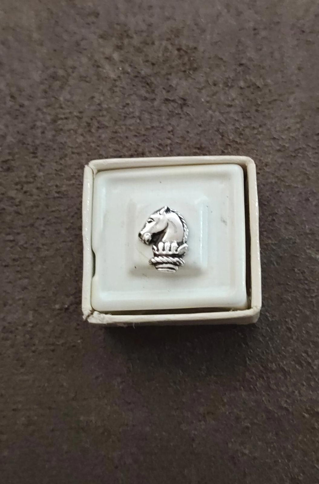 Silver-tone horse head tie tack pin viewed slightly from above