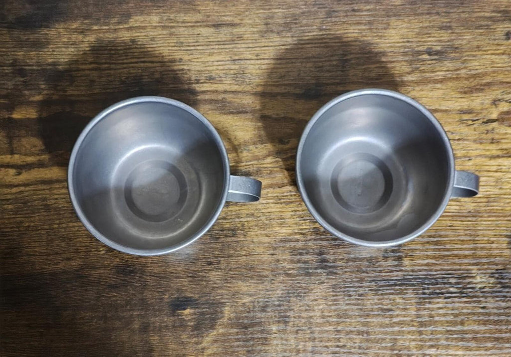 Bottom view of two stainless steel mugs with handles, silver interior