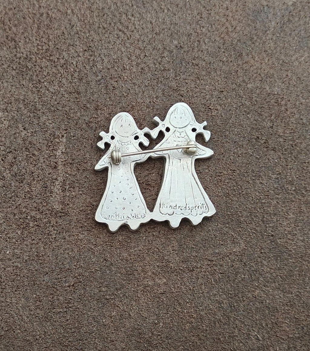 Silver-tone back view pin of two girls holding hands with engraved wording
