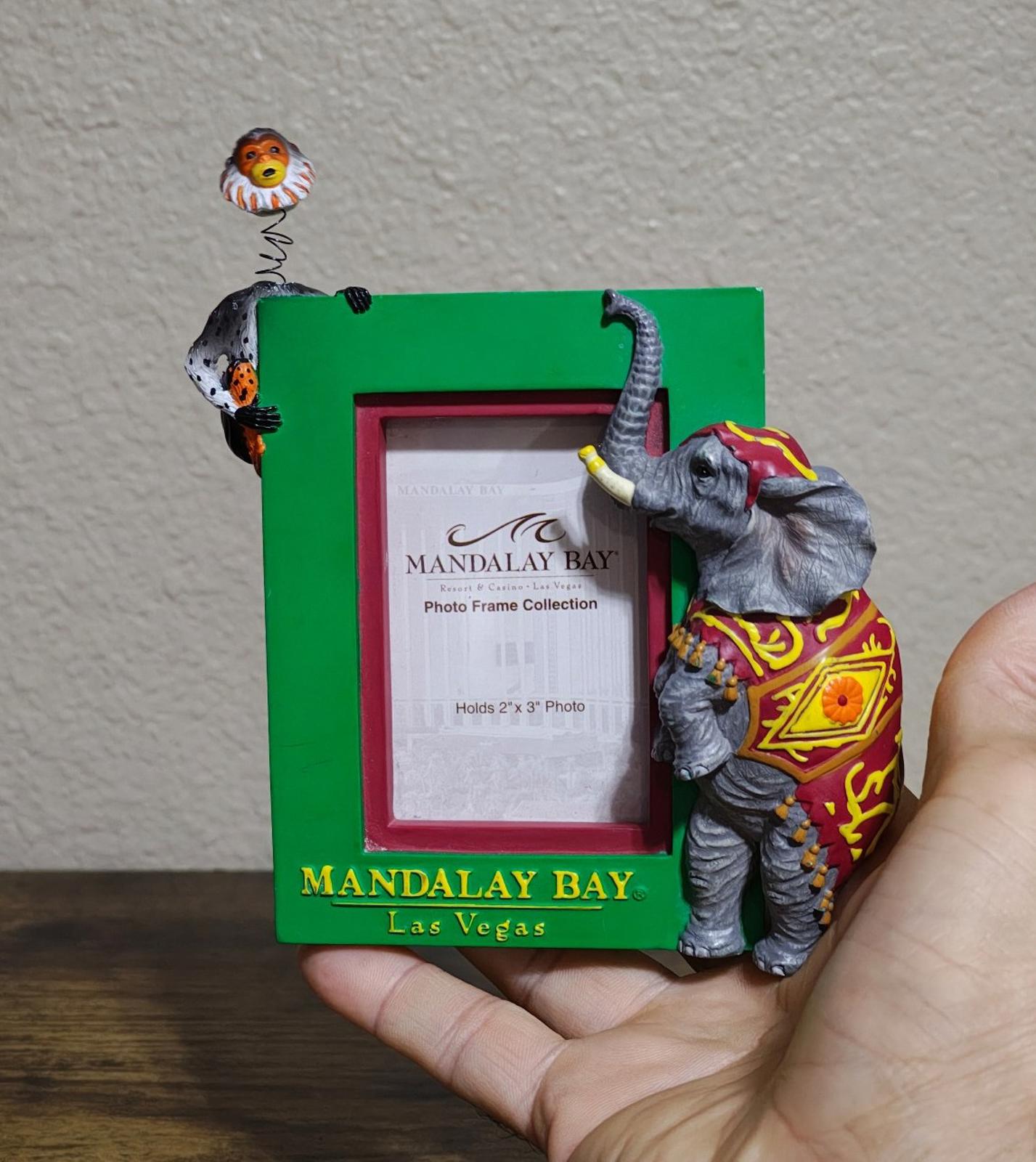 Green souvenir photo frame with elephant and monkey figurines on the front