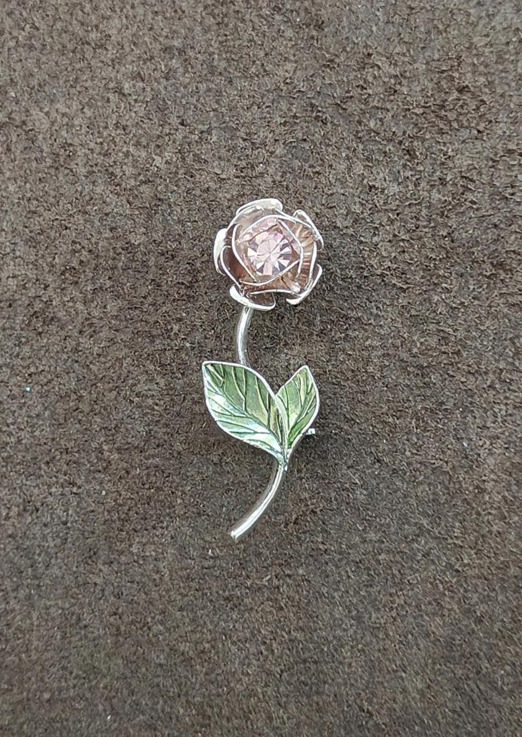 Silver-tone brooch with rhinestone flower head and green enamel leaf, curved pin stem