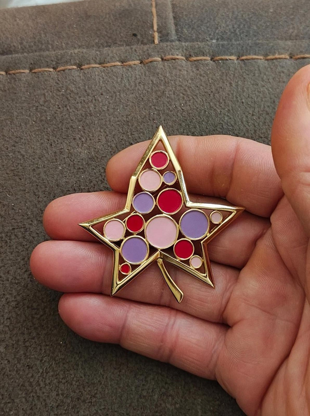 Crown Trifari gold star brooch with red, purple, and pink round enamel cabochons