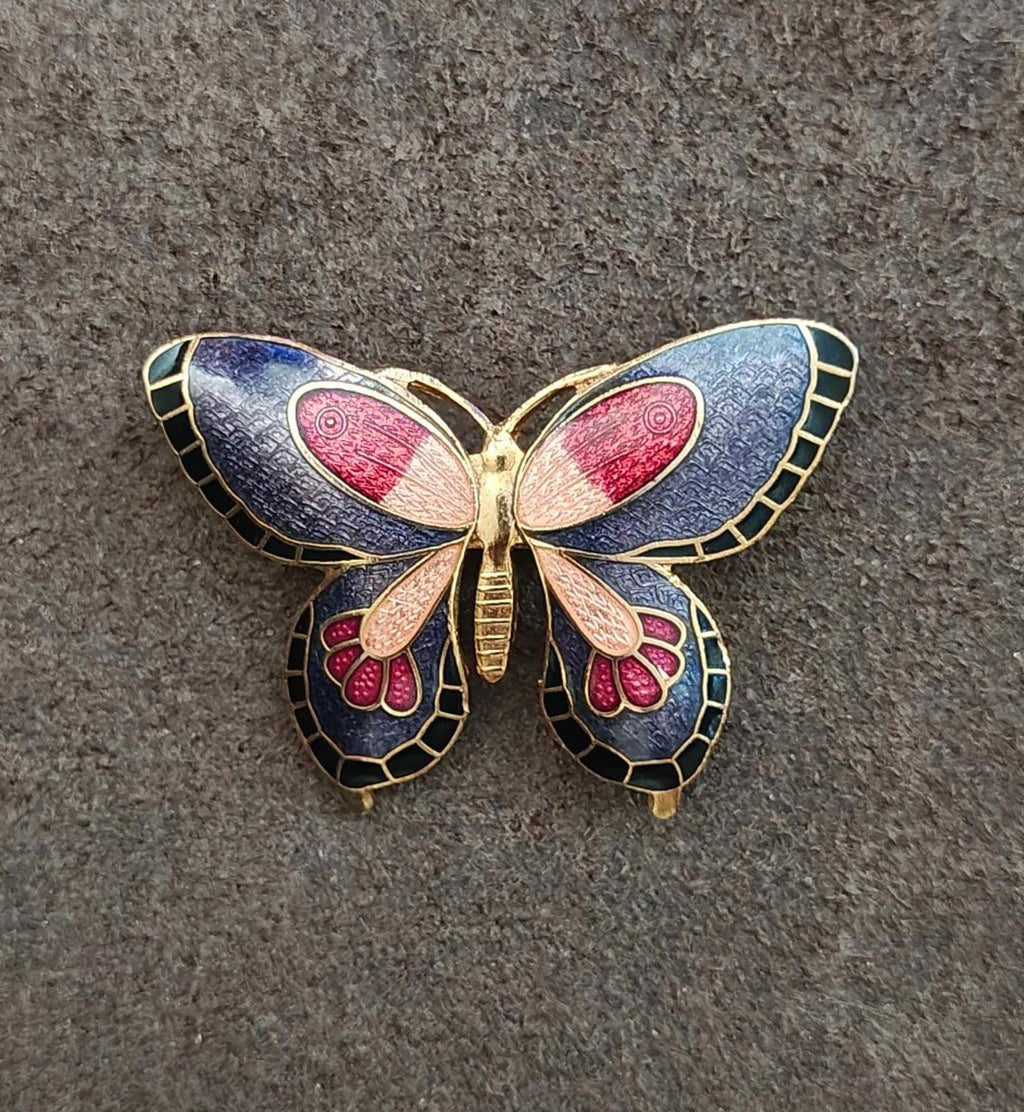 Butterfly enamel brooch, front view with blue wings, red centers, and gold frame