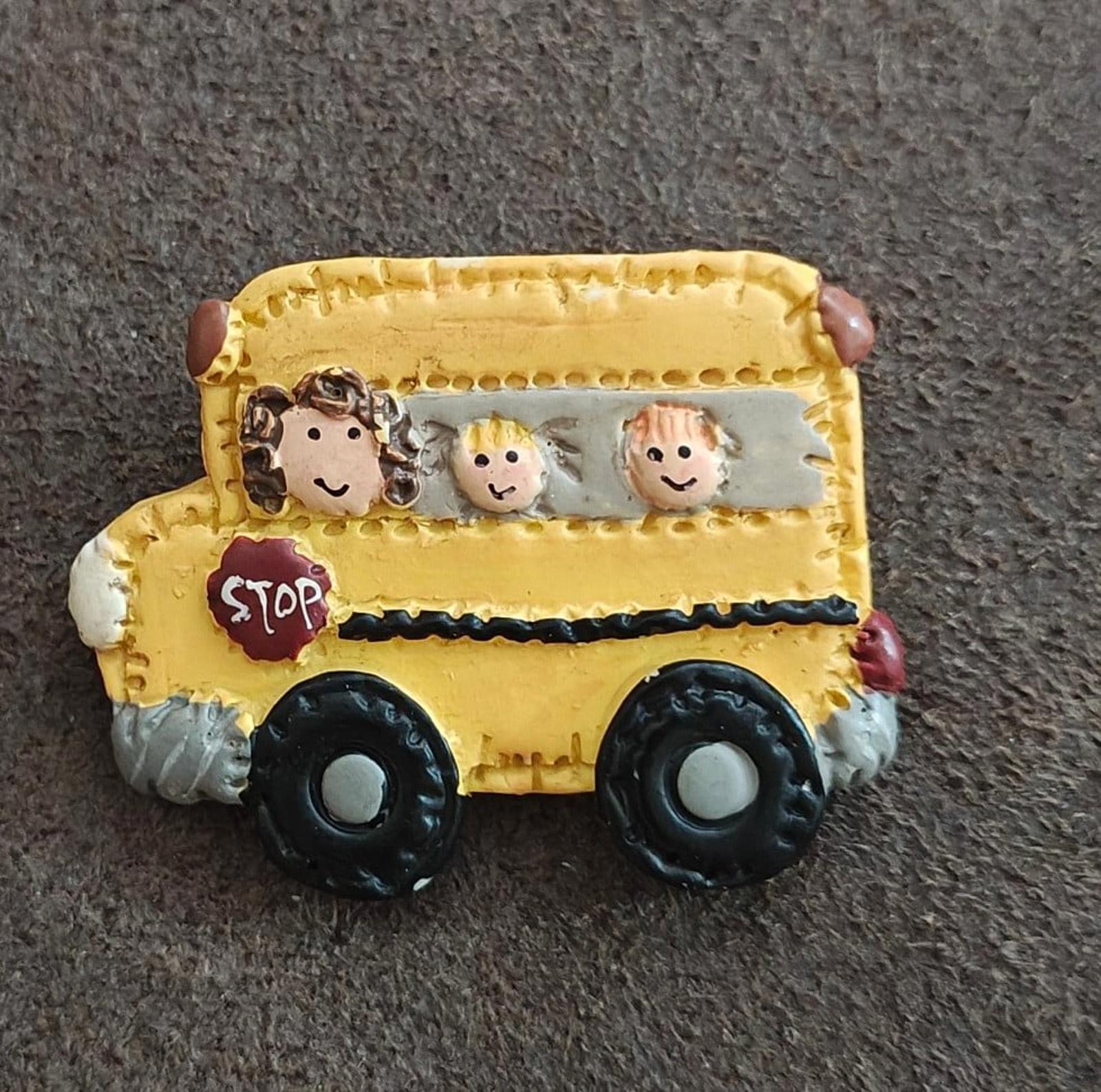 Yellow school bus resin pin showing cartoon kids in window and black wheels
