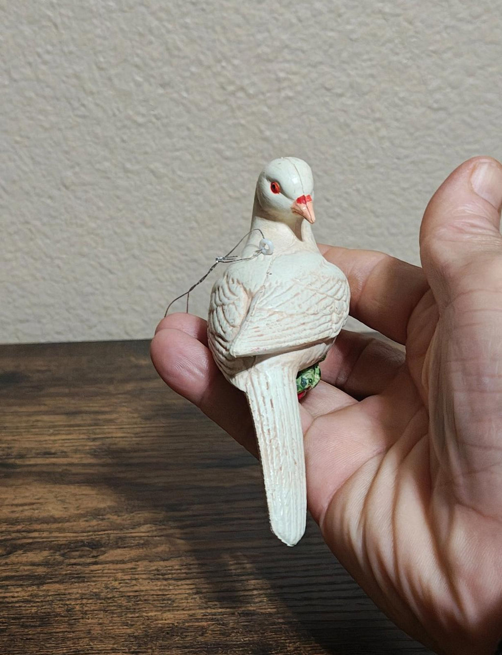White plastic dove ornament back view with hanging string and green scarf detail.