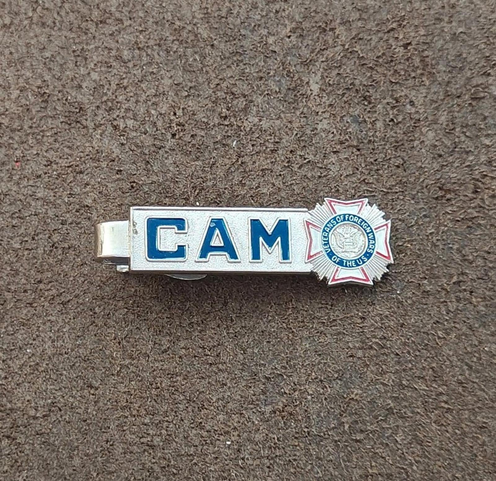 Silver-tone tie bar clip with blue “CAM” lettering and star badge emblem