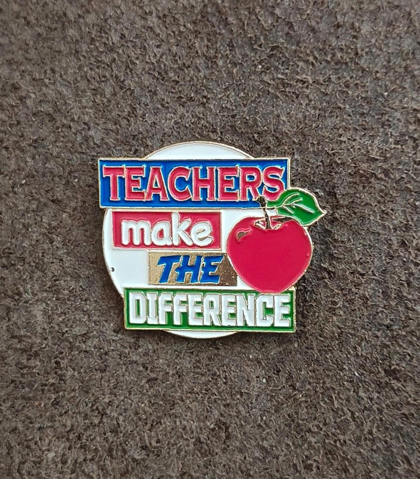 Enamel teacher pin with red apple, green leaf, and “Teachers make the difference”