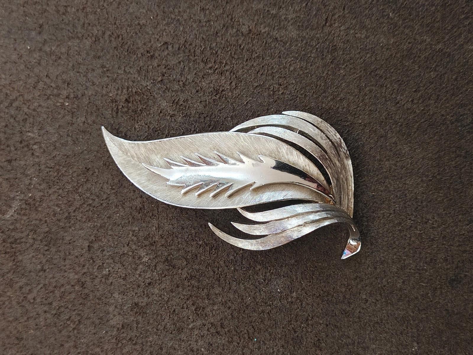 Silver-tone leaf brooch with flowing layered leaves, angled side view