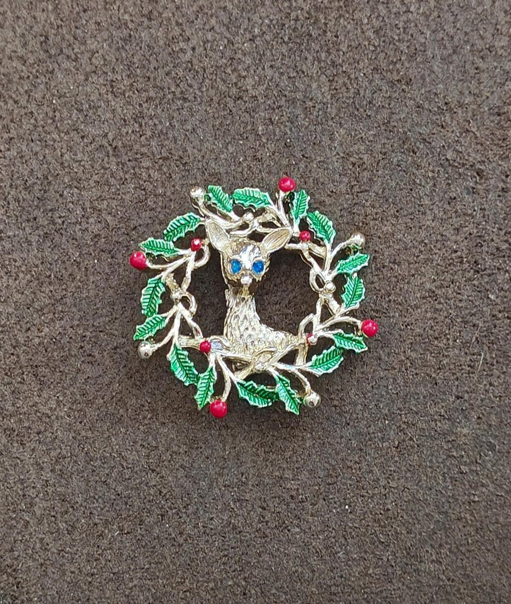 Small holly wreath reindeer brooch with green leaves, red berries, and blue enamel accent