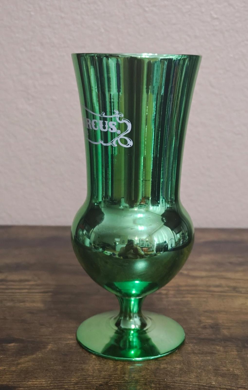 Green mirrored hurricane glass, close side view with Circus Circus logo lettering.