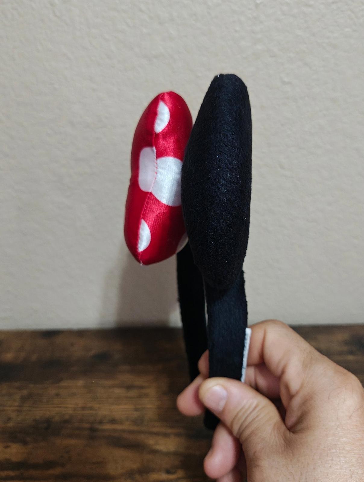 Side view of red and white polka-dot bow ear headband with black fabric ears
