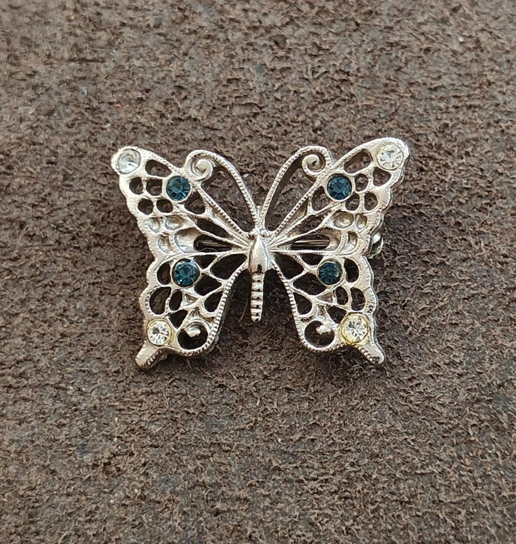 Silver-tone butterfly brooch with detailed filigree and clear plus blue rhinestones