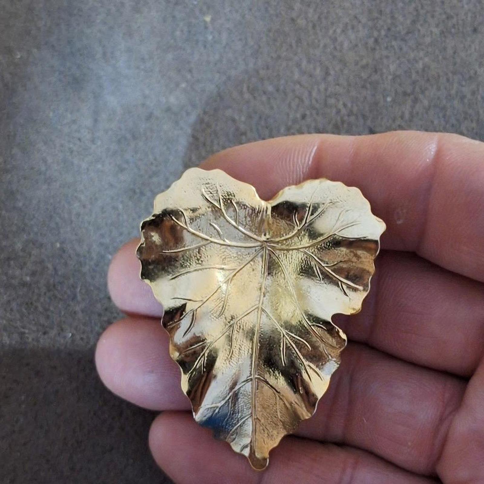 Shiny gold-tone leaf scarf clip with detailed vein texture, shown close-up