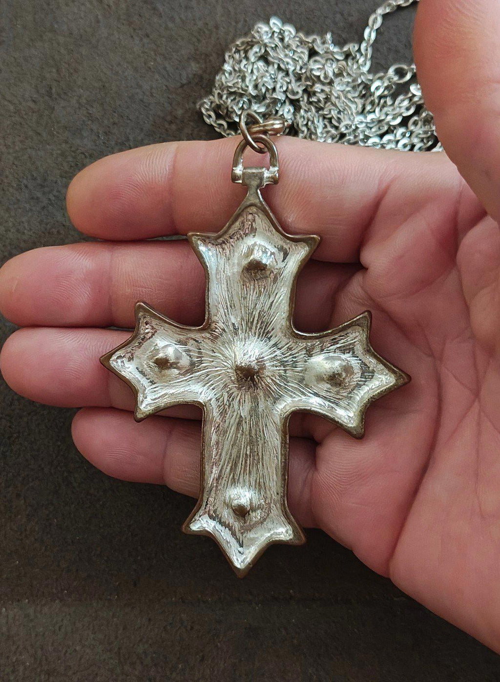 Silver tone cross pendant necklace with all-over textured finish, no red stones visible