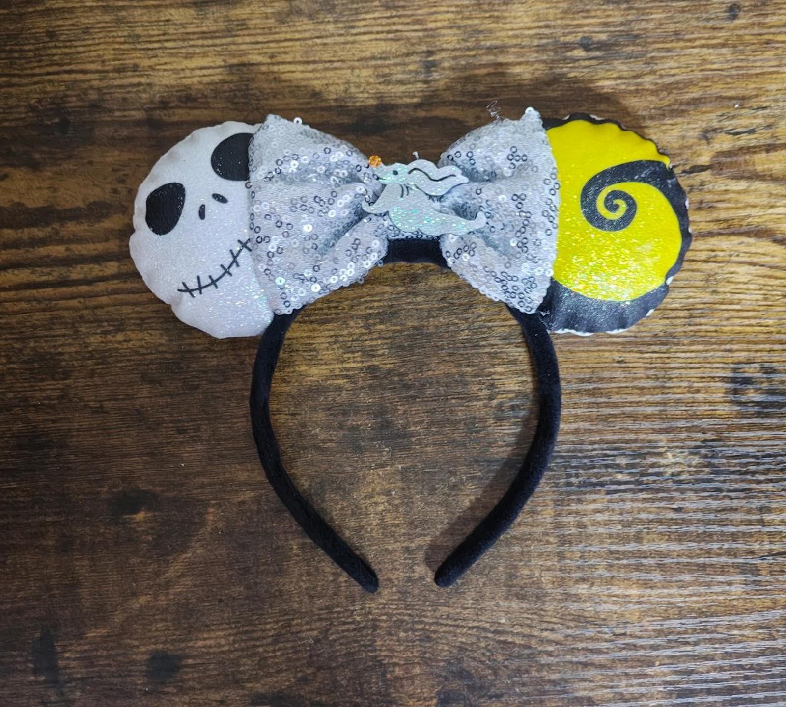 Silver sequin bow headband with skull face, black ears, and yellow swirl side