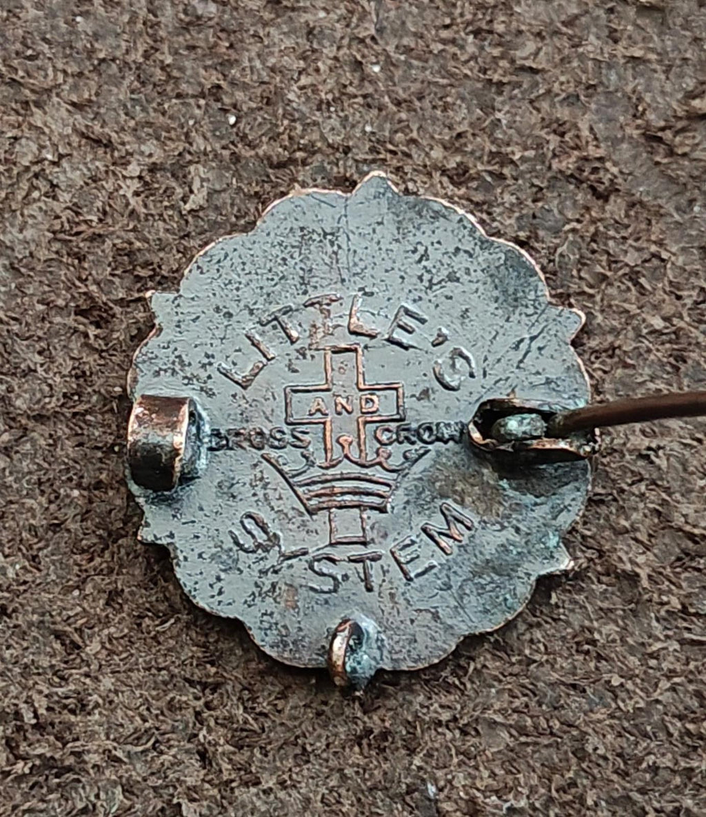 Bronze pin back stamped with cross and letters, safety pin bar visible
