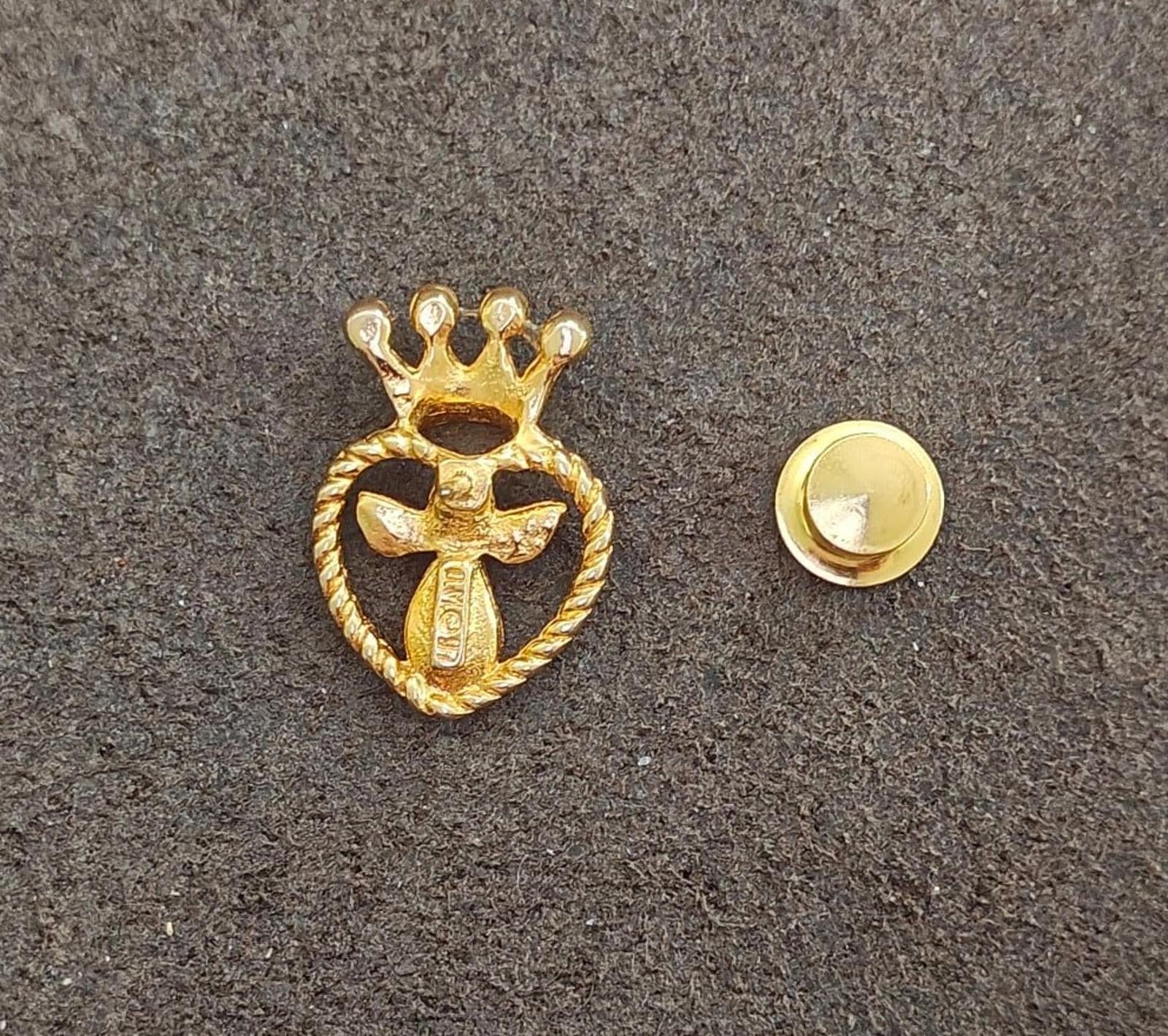 Gold-tone heart crown pin front with angel motif alongside round pin back clasp