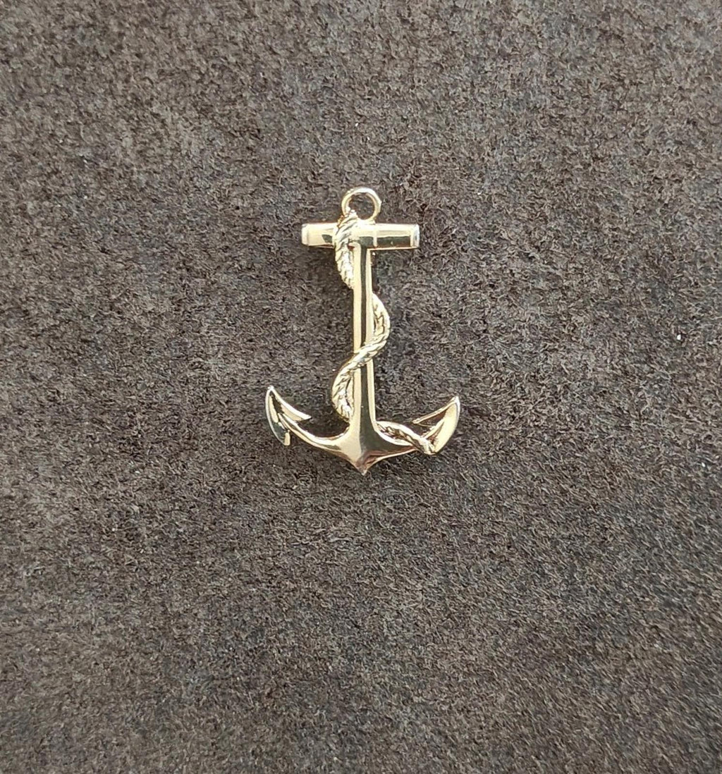 Gold-tone anchor pendant on textured surface, centered front view with loop