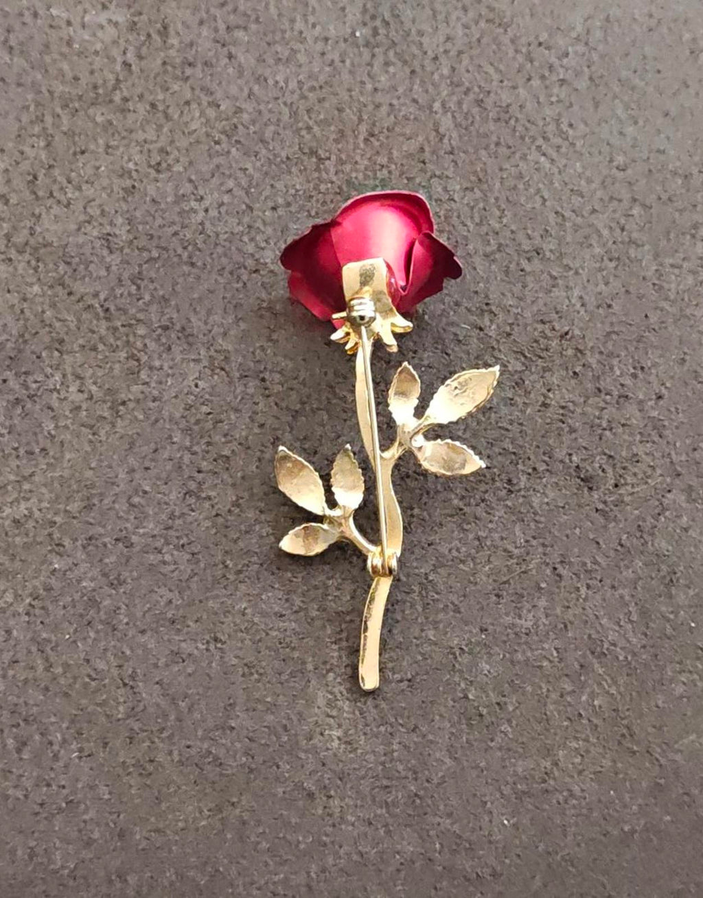 Red rose head with gold-tone stem and leaf brooch, angled view
