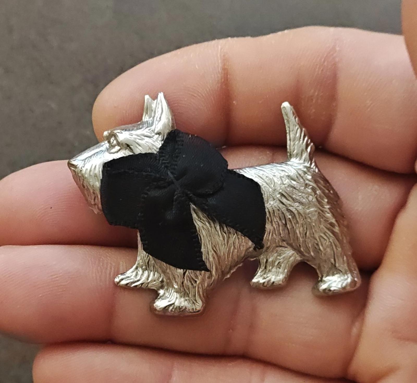 Silver-tone Scottish terrier brooch with a black bow and raised dog figure