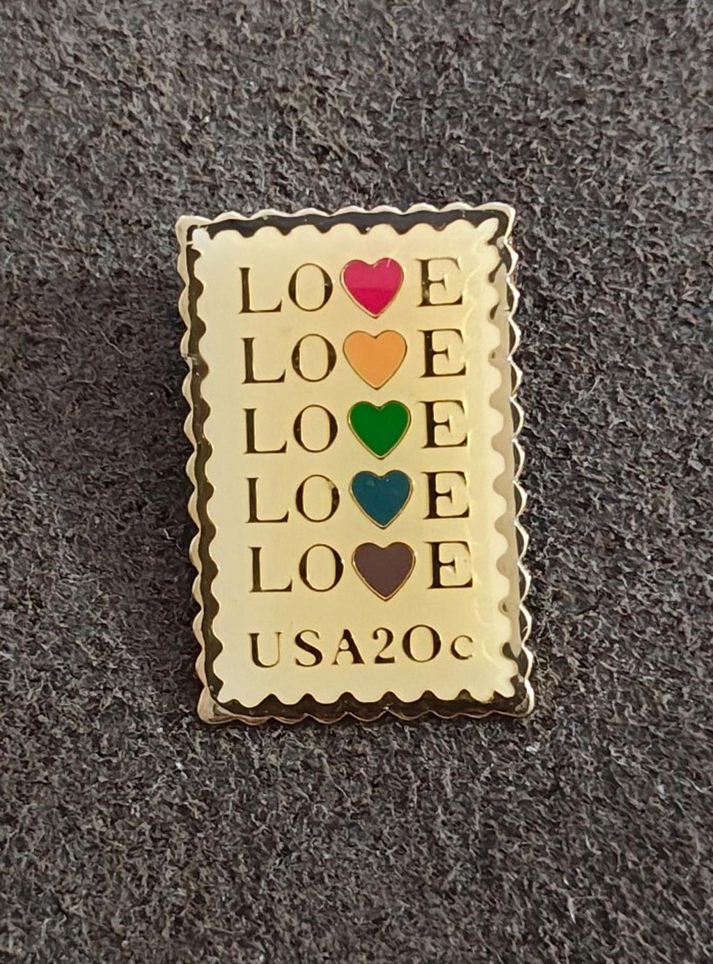 Rectangular gold-tone enamel pin featuring “LOVE” in rows with red, orange, green, and blue hearts.