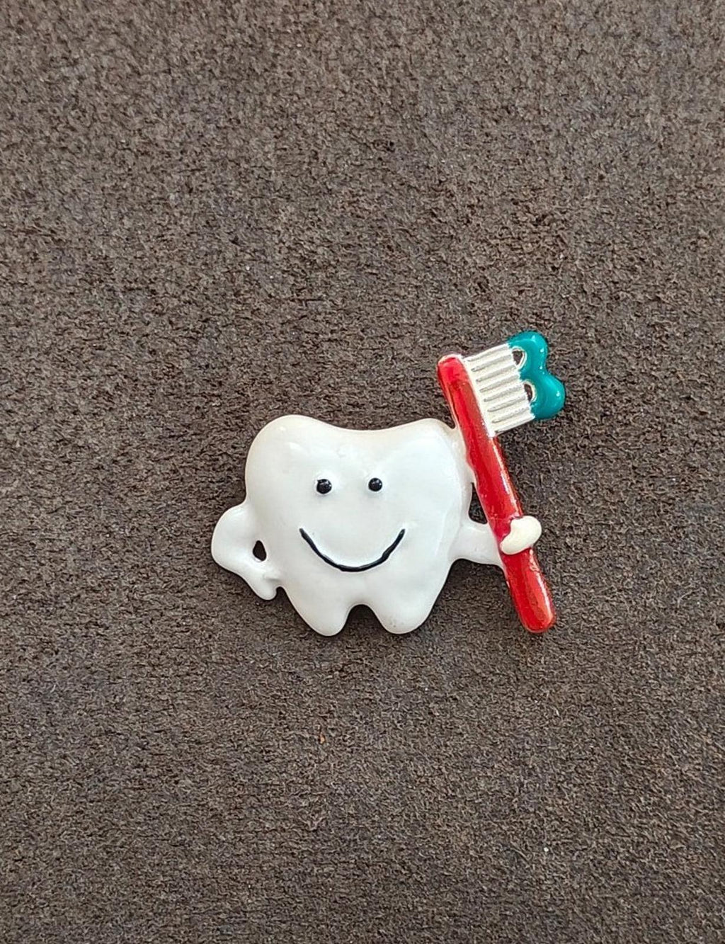Tooth and toothbrush enamel pin with smiling white tooth and red handle, teal brush head.