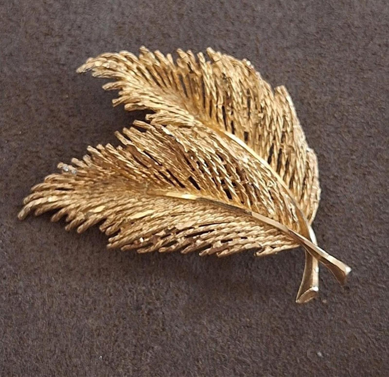 Gold-tone feather leaf brooch with layered texture and central vein, shown flat