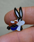Enamel pin of Bugs Bunny holding a carrot, black ears, white face, blue body, orange details