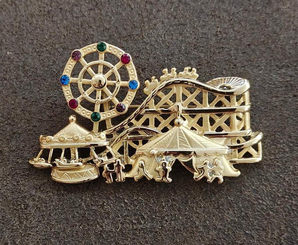 Gold tone carnival brooch showing roulette wheel and carousel horses under canopy