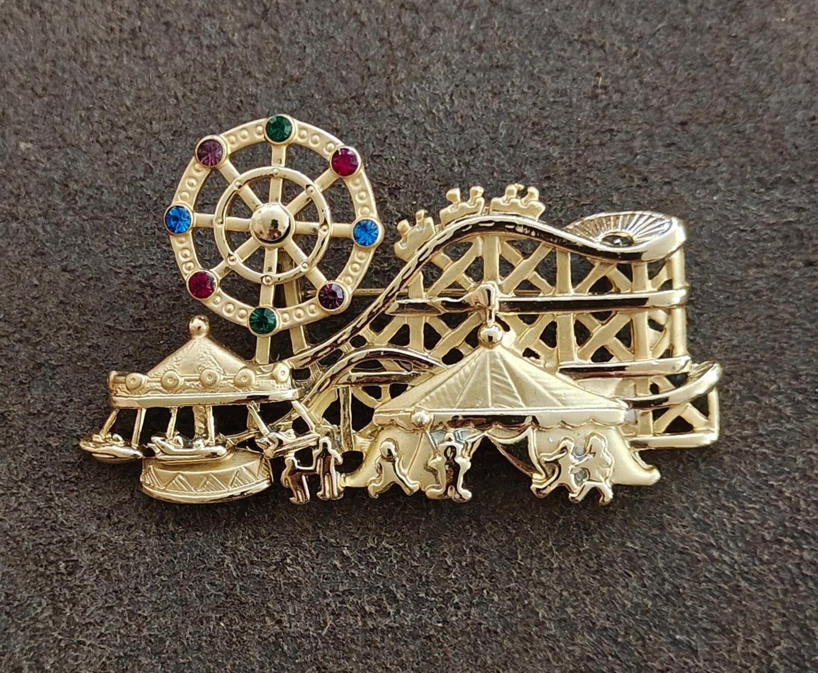 Gold tone carnival brooch showing roulette wheel and carousel horses under canopy