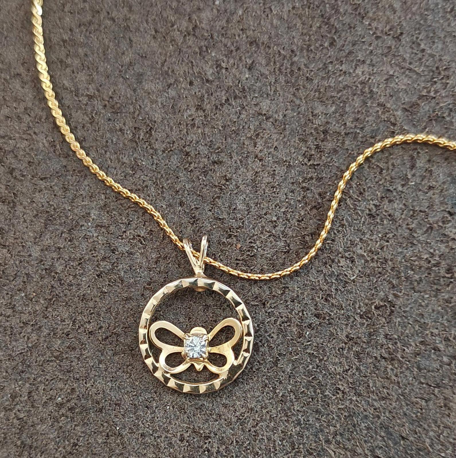 Gold-tone round pendant necklace with bow butterfly motif and clear rhinestone center