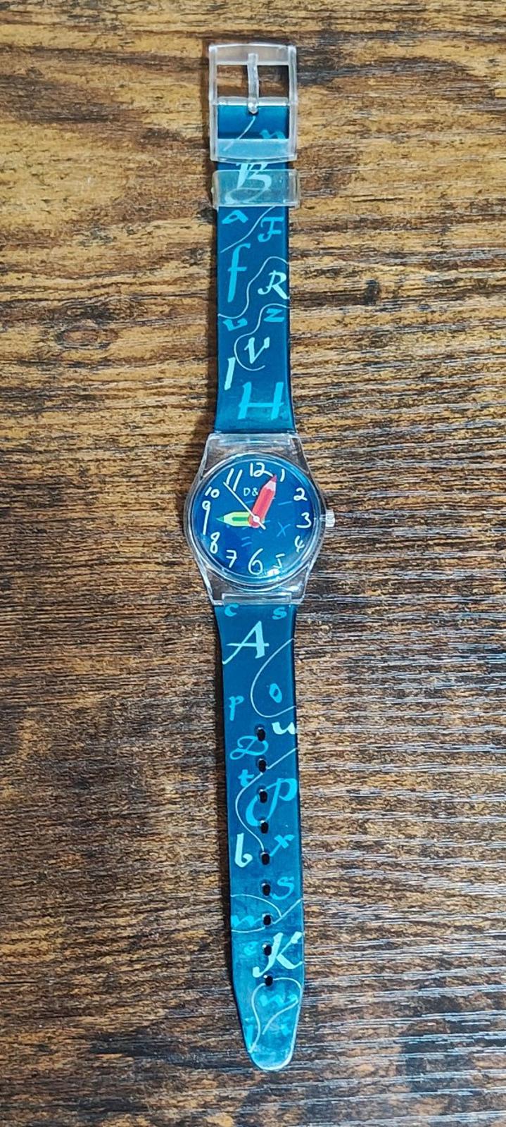 Blue teacher watch with long printed number/letter strap and round blue dial in silver case