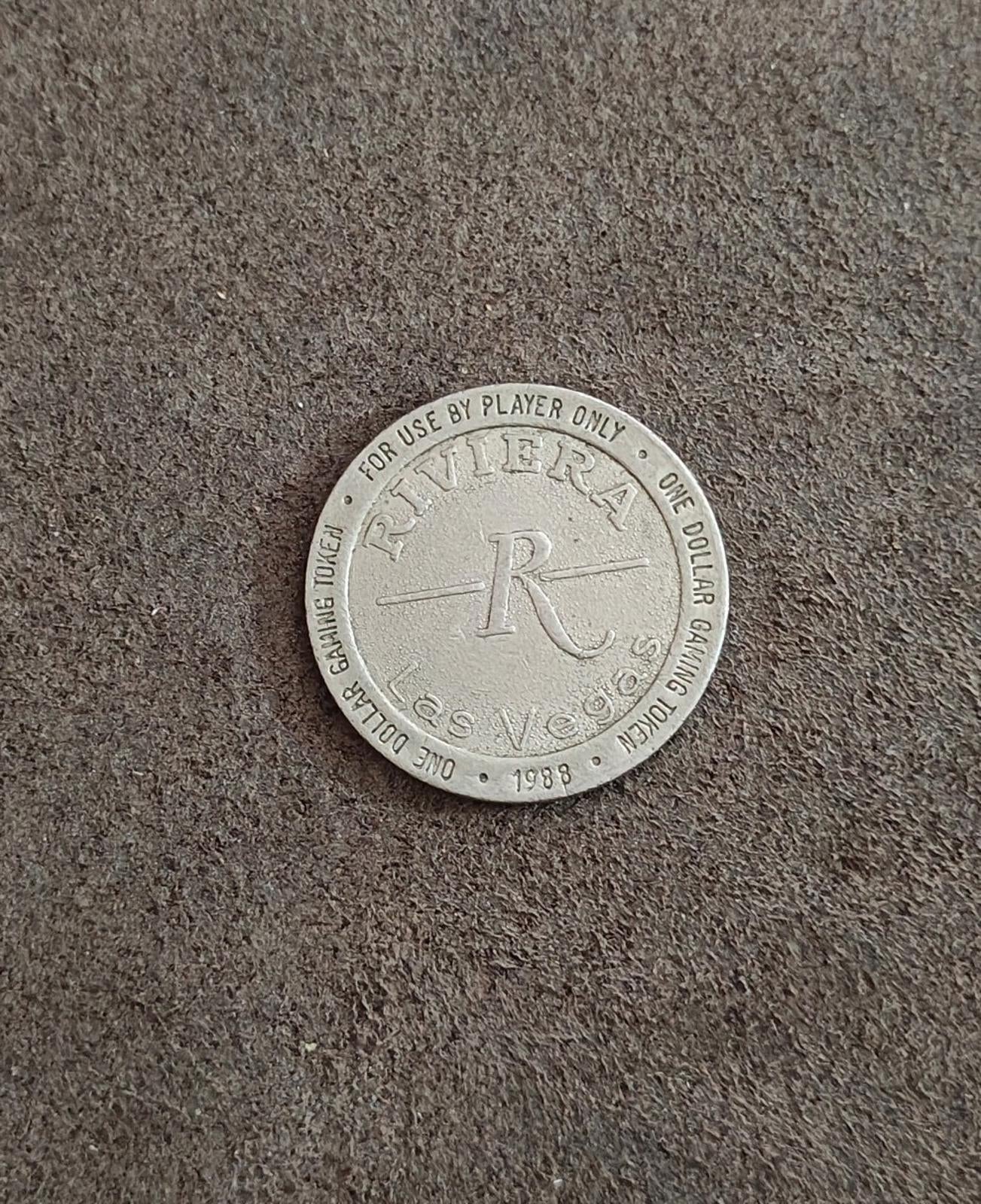 Silver one-dollar gaming token lying flat with Riviera logo and one dollar ring text