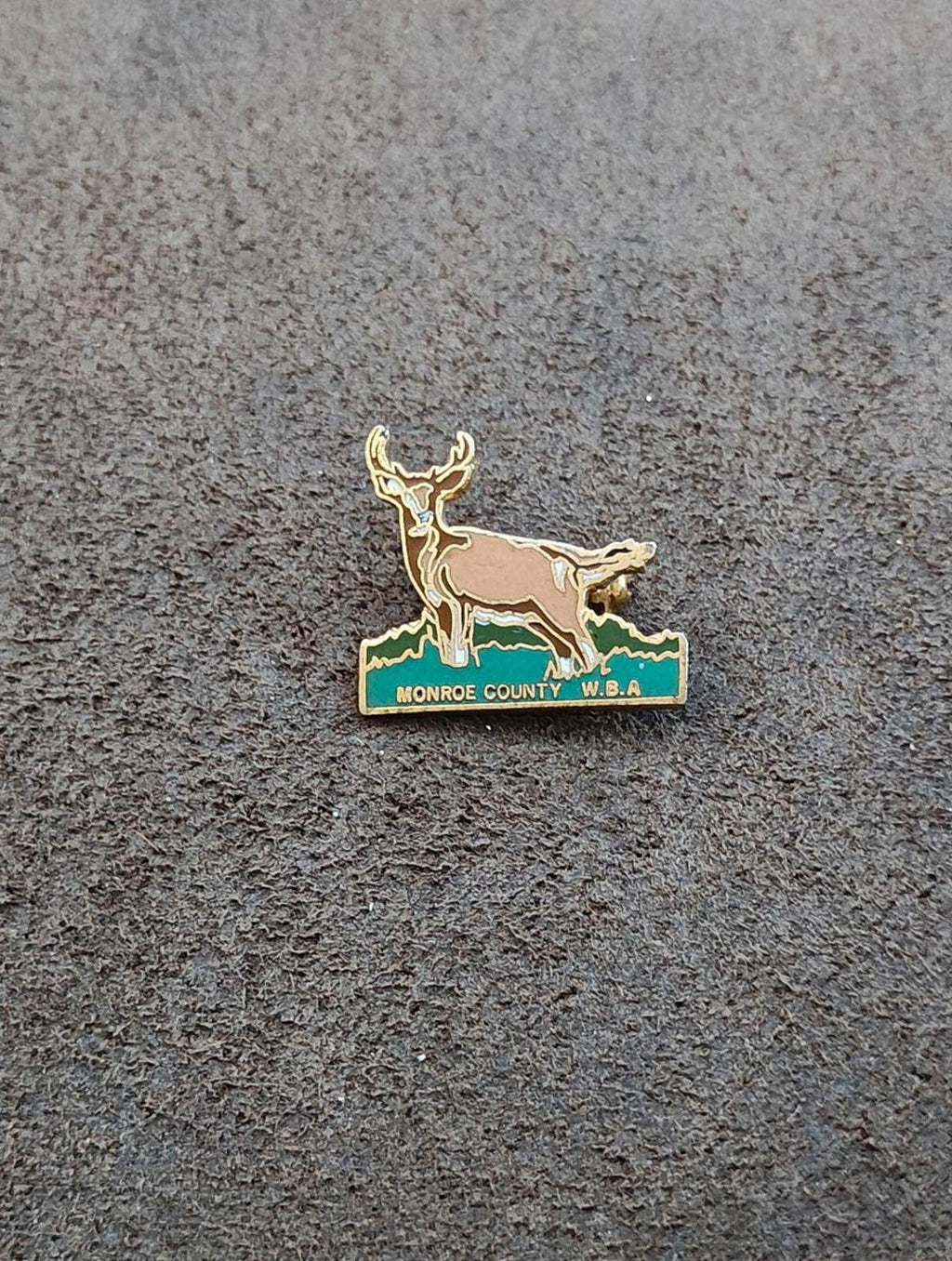 Gold-tone deer enamel pin on green banner with Monroe County W.B.A. text