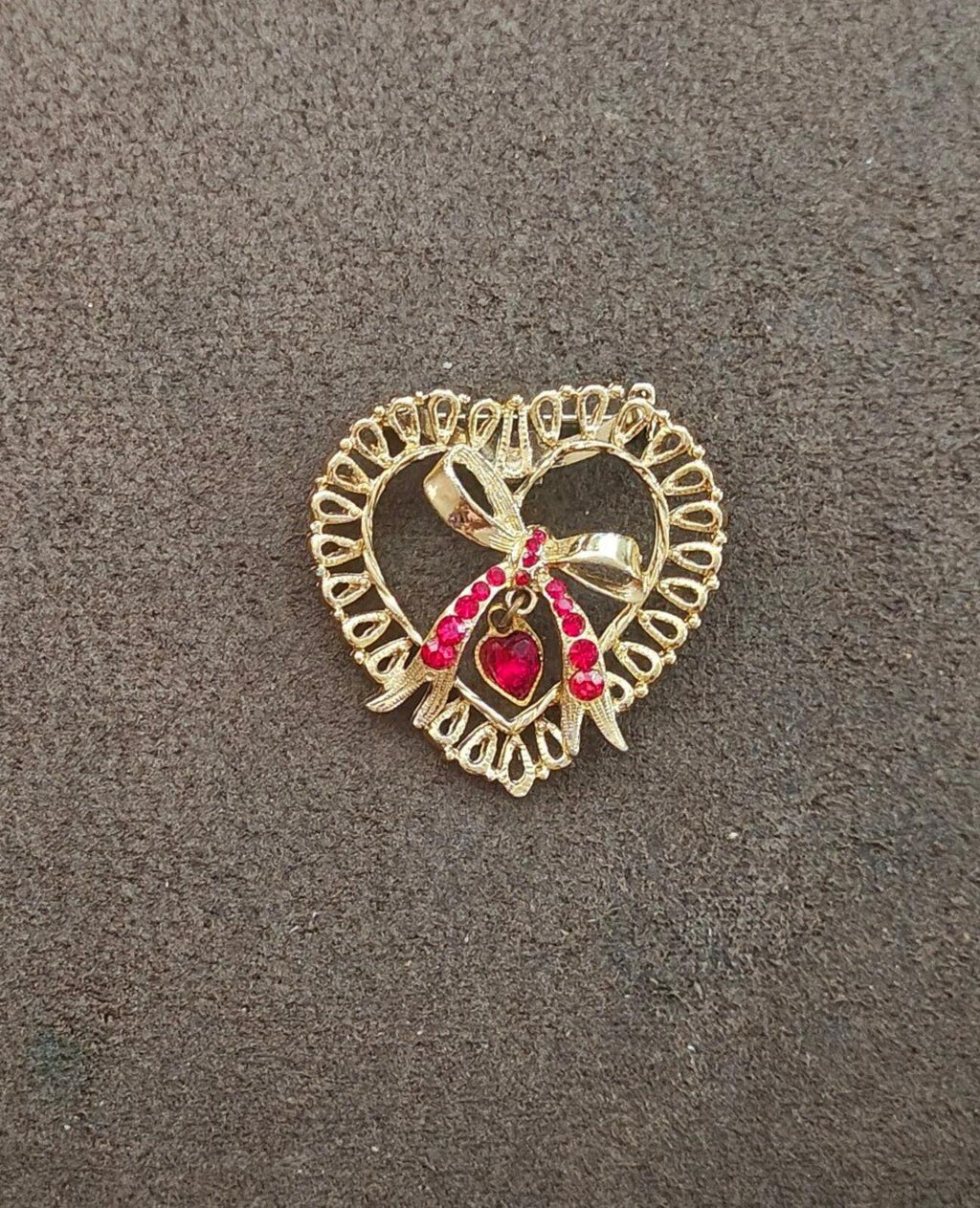 Gold tone heart brooch with red rhinestone details and dangling heart centerpiece