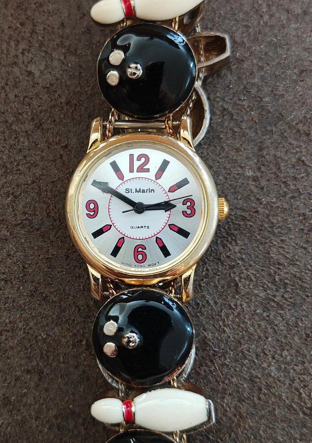 Ladies novelty watch front view: white dial with red/black markers, gold case, black and white accents